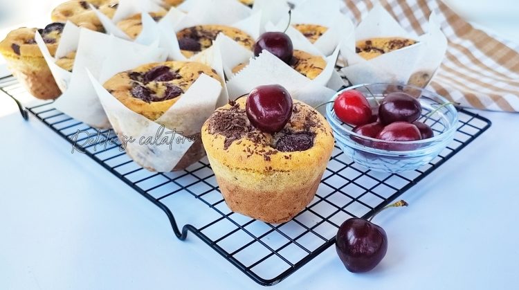 Briose pandispan cu cirese si ciocolata aseyate pe un gratar de racire, inconjurate de cateva cirese proaspete